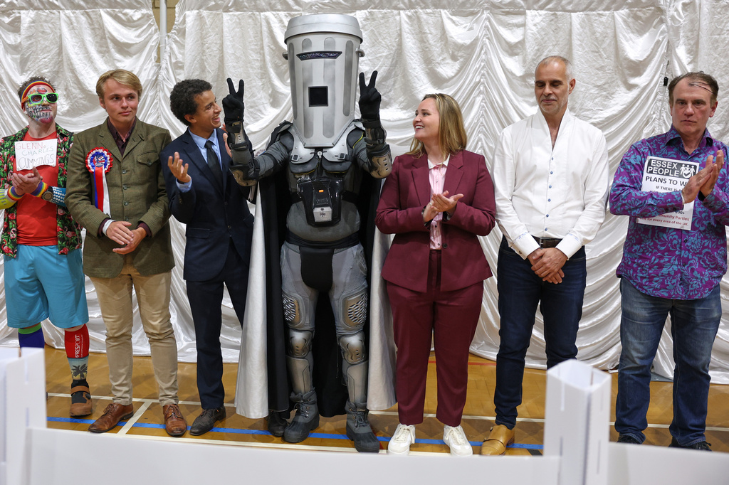 Count Binface, center, stands among other candidates during the result announcement after the Clacton by-election count at the Leisure Centre in Clacton on Sea, England, Friday, Aug. 14, 2026.(AP Photo/Richard Pelham)