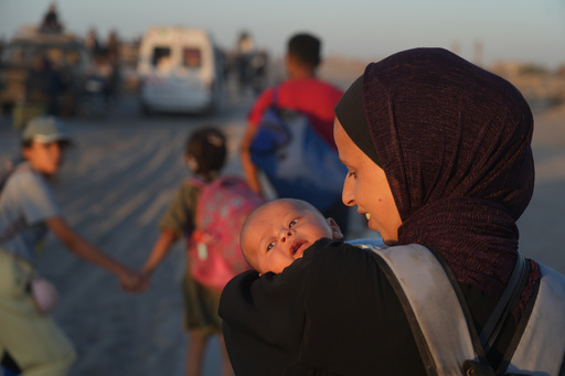 A displaced Palestinian woman carries her baby as she walks with others along the coastal road near Wadi Gaza in the central Gaza Strip, heading toward Gaza City, Friday, Oct. 10, 2025, after Israel and Hamas agreed to a pause in their war and the release of the remaining hostages. (AP Photo/Abdel Kareem Hana) A displaced Palestinian woman carries her baby as she walks with others along the coastal road near Wadi Gaza in the central Gaza Strip, heading toward Gaza City, Friday, Oct. 10, 2025, after Israel and Hamas agreed to a pause in their war and the release of the remaining hostages. (AP Photo/Abdel Kareem Hana)
