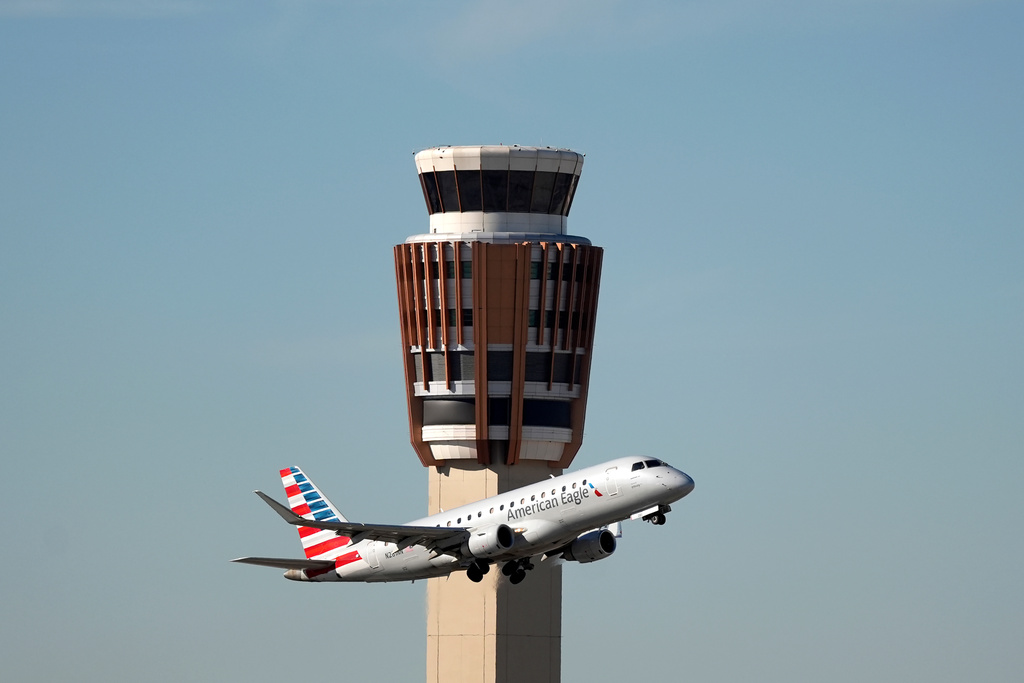 FILE - An American Airlines American Eagle jet flies past the air traffic control tower at Phoenix Sky Harbor International Airport, Nov. 8, 2025, in Phoenix. (AP Photo/Ross D. Franklin, file)