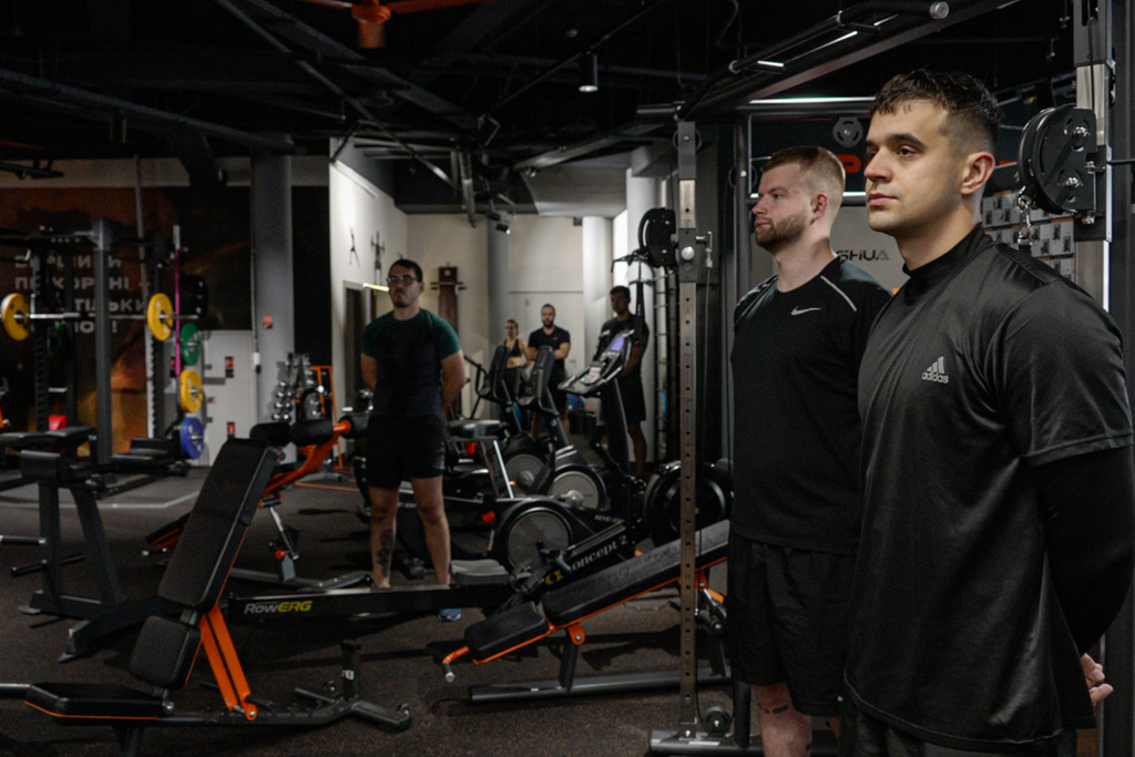 People stand in a gym during a nationwide minute of silence in memory of fallen soldiers, who defended their homeland in the war with Russia, in downtown Kyiv, Ukraine, Monday, Oct. 6, 2025. (AP Photo/Alex Babenko)
