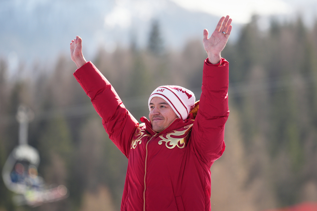 Aleksei Bugaev, of Russia, waves from the podium after winning the bronze medal in the alpine skiing men's downhill standing competition at the 2026 Winter Paralympics, in Cortina d'Ampezzo, Italy, Saturday, March 7, 2026. (AP Photo/Emilio Morenatti)