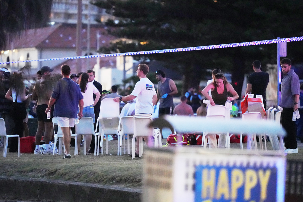 People and emergency workers gather at location where a holiday event was taking place and then a reported shooting at Bondi Beach in Sydney, Sunday, Dec. 14, 2025. (AP Photo/Mark Baker)