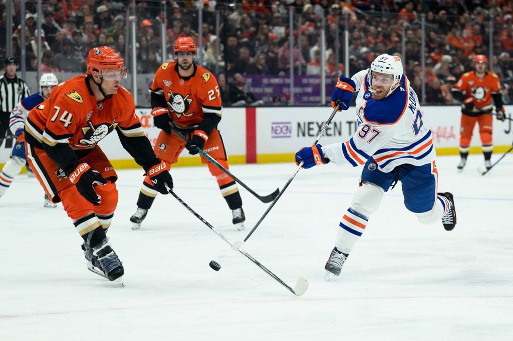Edmonton Oilers center Connor McDavid, right, shoots as Anaheim Ducks defenseman John Carlson, left, defends during the second period of Game 4 in the first round of an NHL hockey Stanley Cup playoff series Sunday, April 26, 2026, in Anaheim, Calif. (AP Photo/Kyusung Gong)