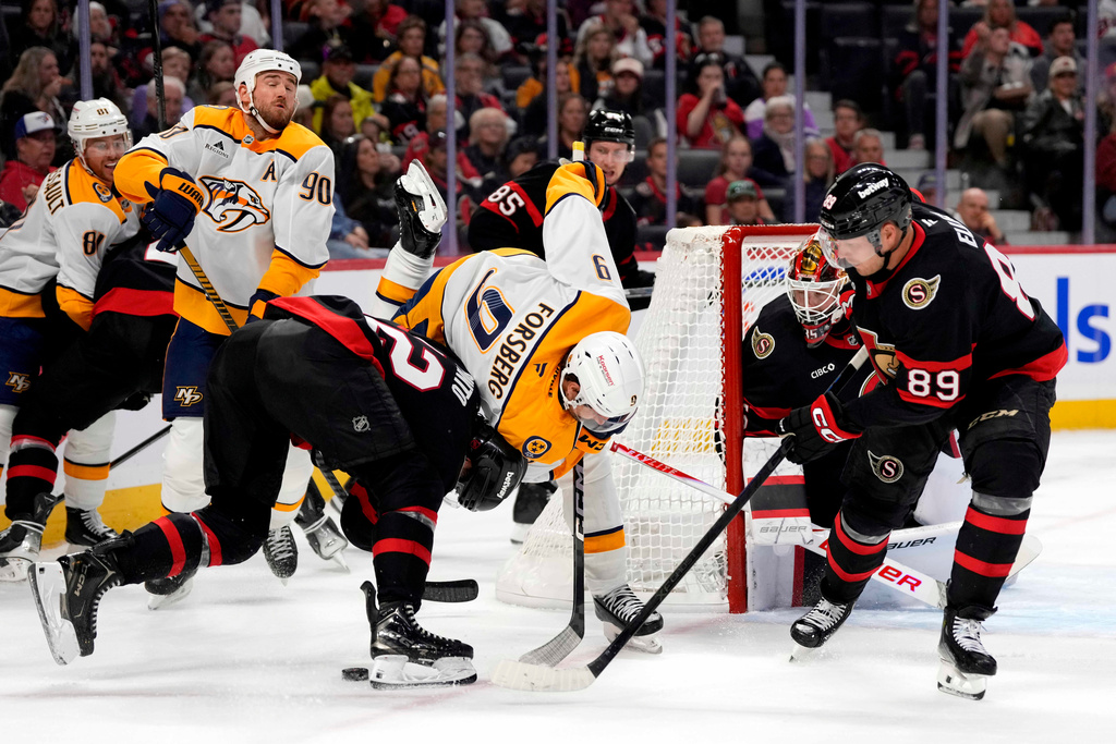 Nashville Predators' Filip Forsberg (9) and Ottawa Senators' Thomas Chabot (72) battle for the puck in front of goaltender Linus Ullmark (35) and Lars Eller (89) during first period NHL hockey action in Ottawa, Monday, Oct. 13, 2025. (Justin Tang/The Canadian Press via AP)
