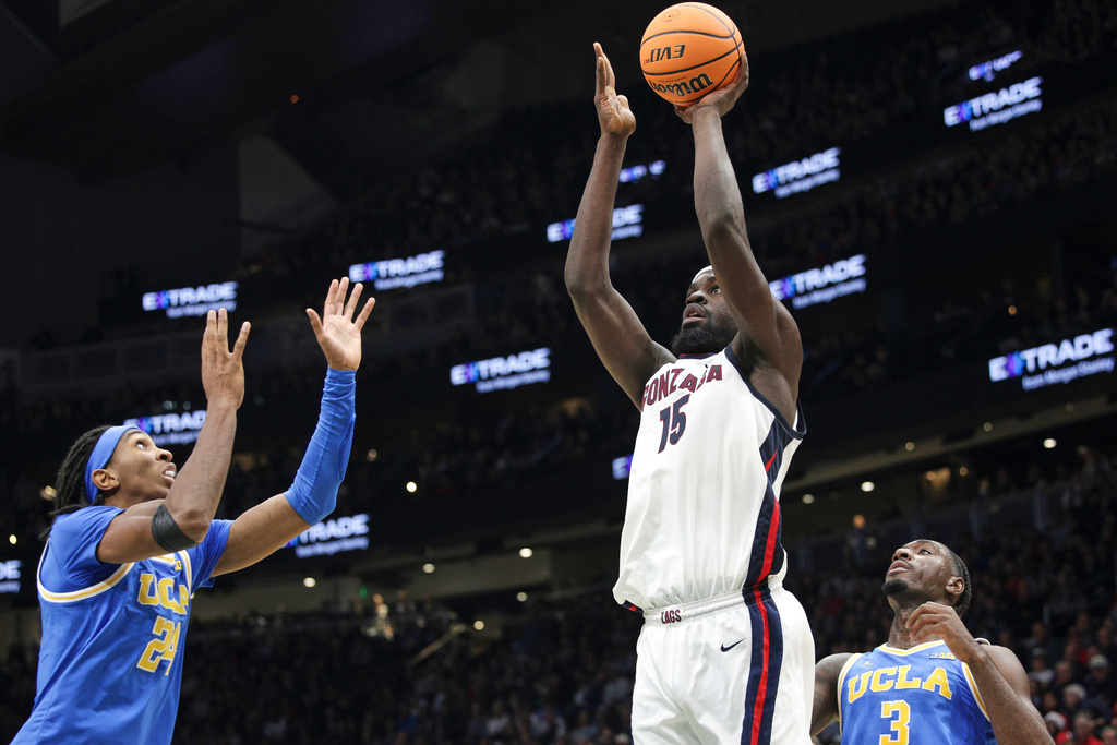 Gonzaga center Graham Ike (15) shoots the ball as UCLA forward/center Steven Jamerson II (24) and guard/forward Eric Dailey Jr. (3) defend during the first half of a NCAA basketball game, Saturday, Dec. 13, 2025, in Seattle. (AP Photo/Jason Redmond)