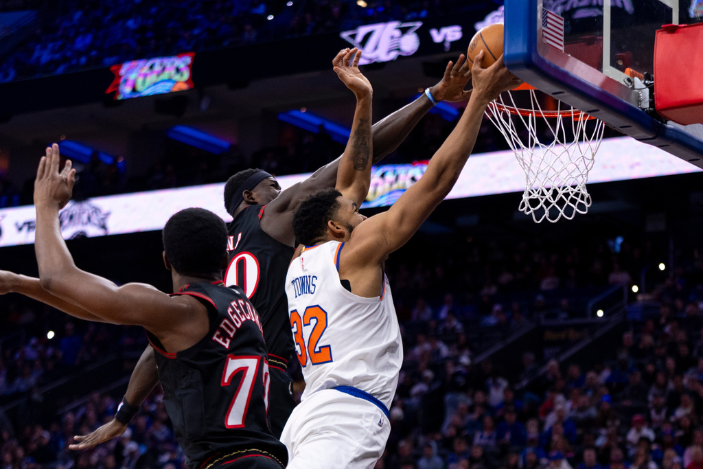 New York Knicks' Karl-Anthony Towns, right, goes up for the shot as Philadelphia 76ers' Adem Bona, center, fouls him with VJ Edgecombe, left, defending during the first half of an NBA basketball game, Saturday, Jan. 24, 2026, in Philadelphia. (AP Photo/Chris Szagola)