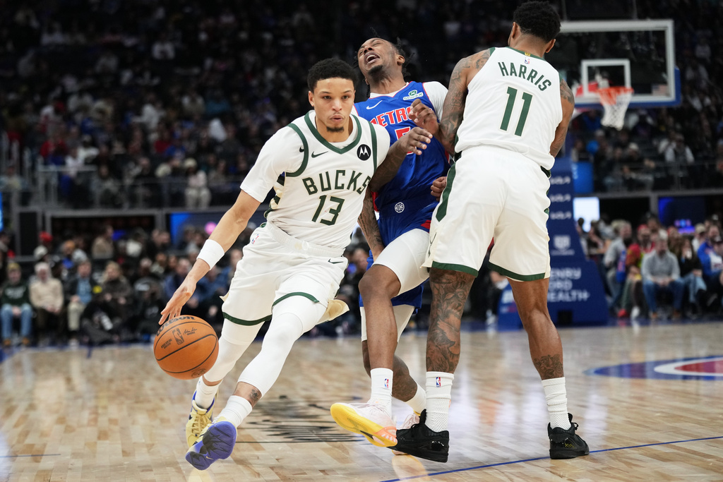 Milwaukee Bucks guard Ryan Rollins, left, drives as guard Gary Harris, right, sets a screen on Detroit Pistons forward Ronald Holland II during the first half of an NBA basketball game, Saturday, Dec. 6, 2025, in Detroit. (AP Photo/Ryan Sun)