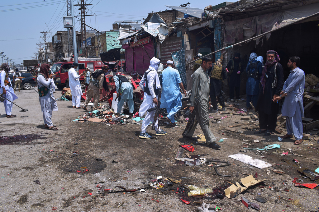Plainclothes police officers examine damage at the site of a bomb explosion at a market in Sarai Norag in Lakki Marwat, a district in Pakistan's Khyber Pakhtunkhwa province, Tuesday, May 12, 2026. (AP Photo/G.A Marwat)