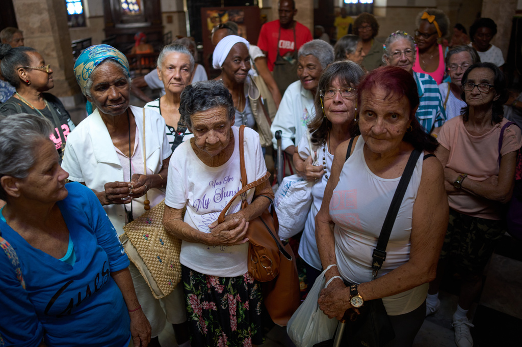 Mercedes Lopez Rey, 83, center front, and other elderly residents wait to be served a free meal in a dining hall adjacent to Church of the Holy Spirit where seniors gather three times a week for a free meal, in Old Havana, Cuba, Wednesday, April 15, 2026. (AP Photo/Ramon Espinosa)