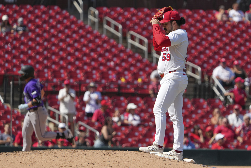 St. Louis Cardinals relief pitcher JoJo Romero (59) adjusts his cap as Colorado Rockies' Hunter Goodman, left, rounds the bases after hitting a two-run home run during the ninth inning of a baseball game Wednesday, Aug. 13, 2025, in St. Louis. (AP Photo/Jeff Roberson)