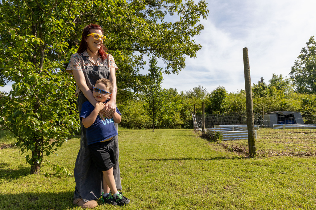 In this photo provided by KOSU, Ashley Caudle, a citizen of the Cherokee Nation, wraps her arms around her son, Elliot, next to her garden in Stilwell, Okla., on Friday, May 1, 2026. (Sarah Liese/KOSU via AP)