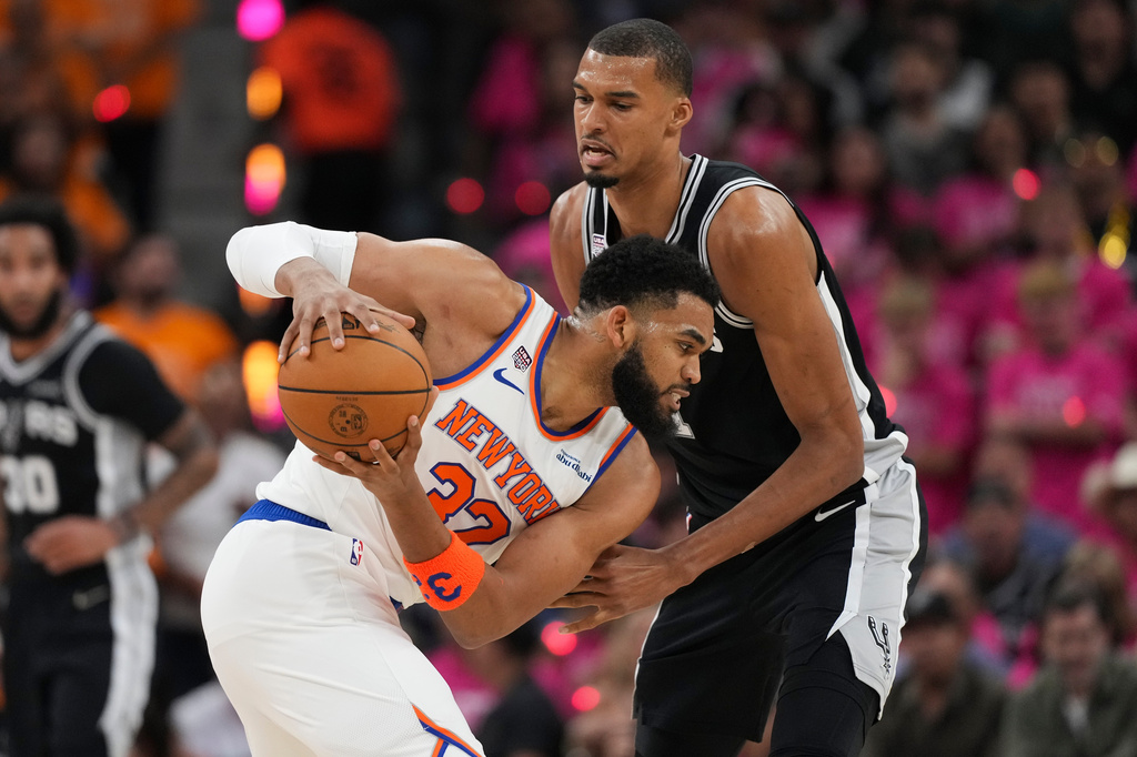 New York Knicks center Karl-Anthony Towns (32) looks to drive past San Antonio Spurs forward Victor Wembanyama during the first half of Game 1 of the NBA Finals basketball series, Wednesday, June 3, 2026, in San Antonio. (AP Photo/Eric Gay)
