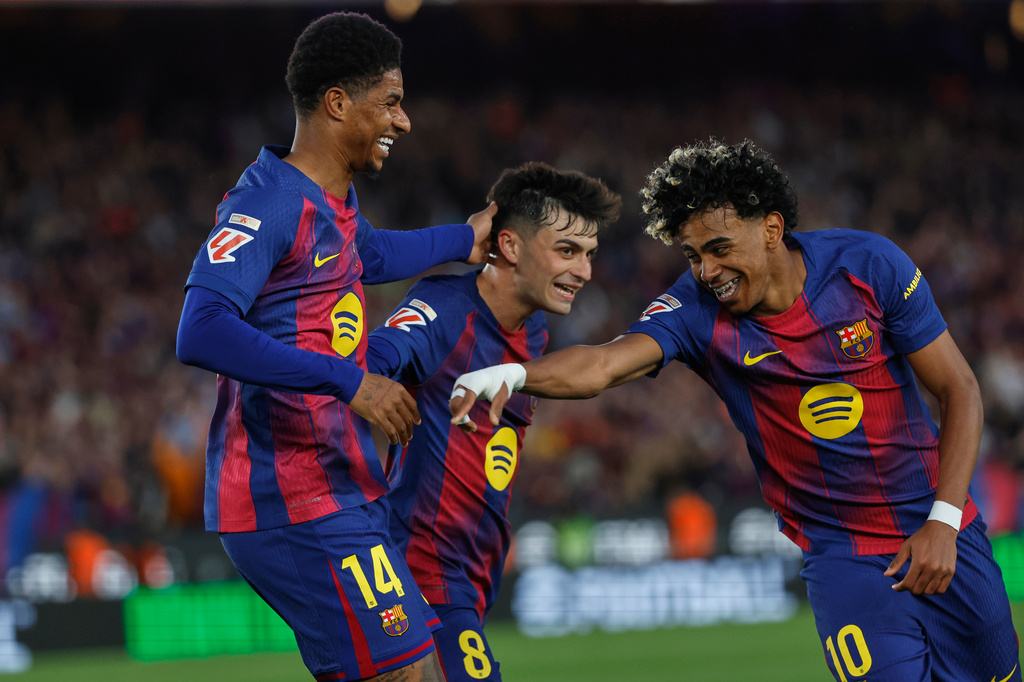 Barcelona's Marcus Rashford, left, celebrates after scoring his side's fourth goal with Lamine Yamal, right, and Pedri during the Spanish La Liga soccer match between Barcelona and Espanyol in Barcelona, Spain, Saturday, April 11, 2026. (AP Photo/Joan Monfort)