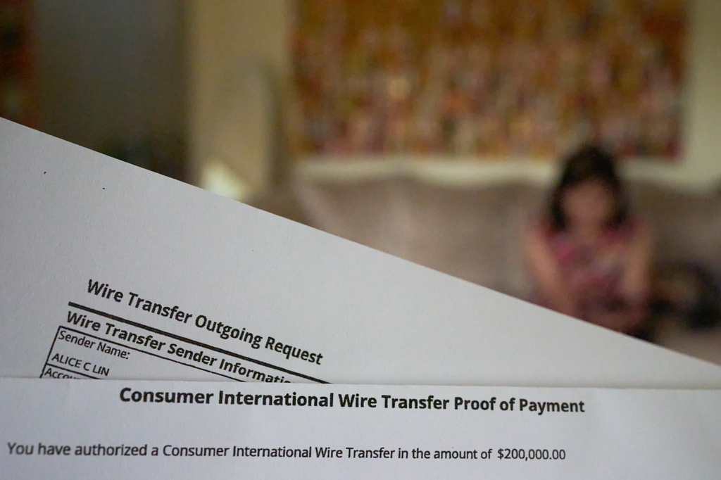 A copy of a wire transfer is seen as Alice Lin, who fought back to recover some of the $720,000 she and her late husband had saved over their lifetime which was stolen by an online scammer, sits on her couch at home, Sunday, May 10, 2026, in Alhambra, Calif. (AP Photo/David Goldman)