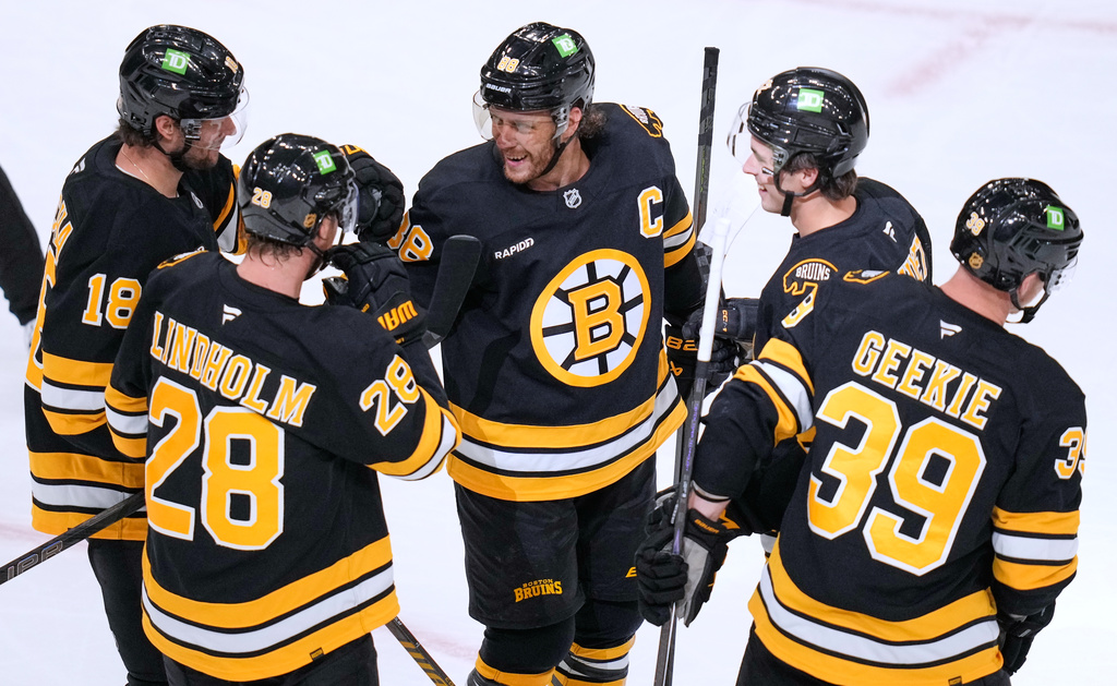 Boston Bruins' David Pastrnak, center, celebrates with teammates after a goal by Morgan Geekie (39) during the second period of an NHL hockey game, Thursday, Oct. 8, 2026, in Boston. (AP Photo/Charles Krupa)