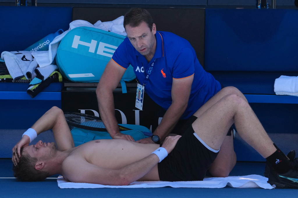 Yannick Hanfmann of Germany receives treatment from a trainer during his second round match against Carlos Alcaraz of Spain at the Australian Open tennis championship in Melbourne, Australia, Wednesday, Jan. 21, 2026. (AP Photo/Dita Alangkara)