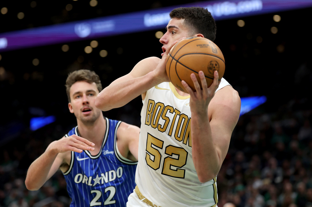 Boston Celtics forward Luka Garza (52) defends the ball from Orlando Magic forward Franz Wagner (22) during the first half of an NBA basketball game, Sunday, April 12, 2026, in Boston. (AP Photo/Mark Stockwell)