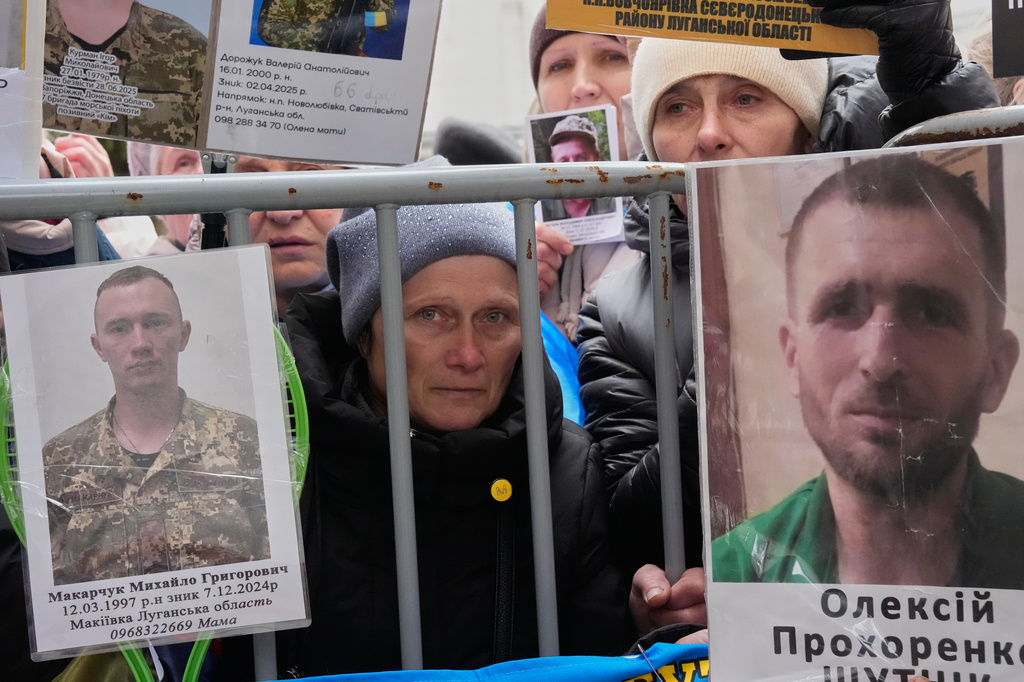 People hold photos of their missed relatives as Ukrainian soldiers return from captivity during a POW exchange between Russia and Ukraine in Chernyhiv region, Ukraine, Saturday, April 11, 2026. (AP Photo/Efrem Lukatsky)