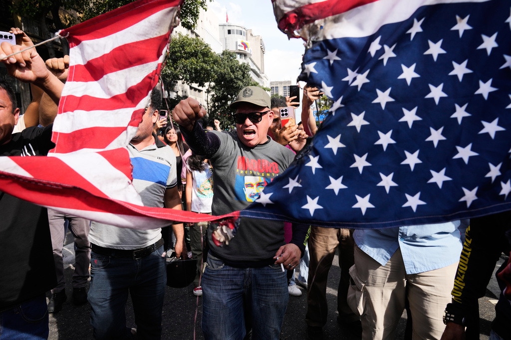 FILE - Government supporters rip an American flag in half during a protest in Caracas, Venezuela, Jan. 3, 2026, after U.S. President Donald Trump announced that U.S. forces had captured President Nicolás Maduro and first lady Cilia Flores. (AP Photo/Ariana Cubillos, File)