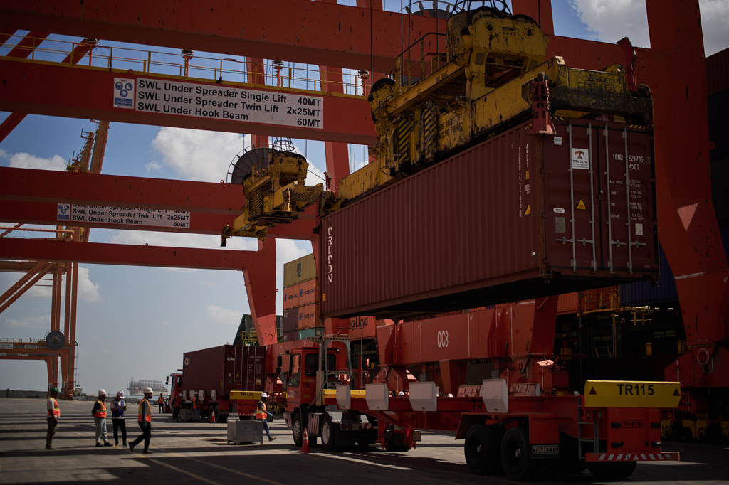 Dockworkers unload cargo containers into trucks at Umm Qasr Port, a deep-water port, in the city of Umm Qasr, Iraq, Friday, March 27, 2026. (AP Photo/Leo Correa)