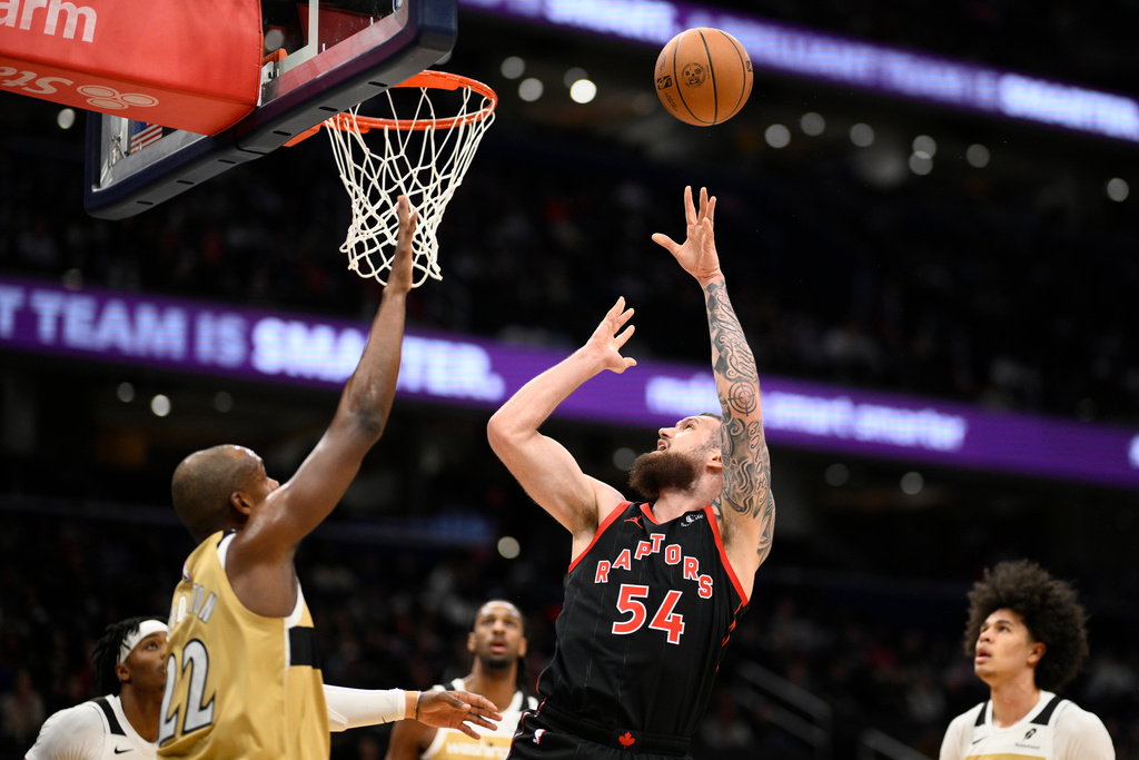 Toronto Raptors forward Sandro Mamukelashvili (54) shoots against Washington Wizards forward Khris Middleton (22) during the first half of an NBA basketball game, Friday, Dec. 26, 2025, in Washington. (AP Photo/Nick Wass)