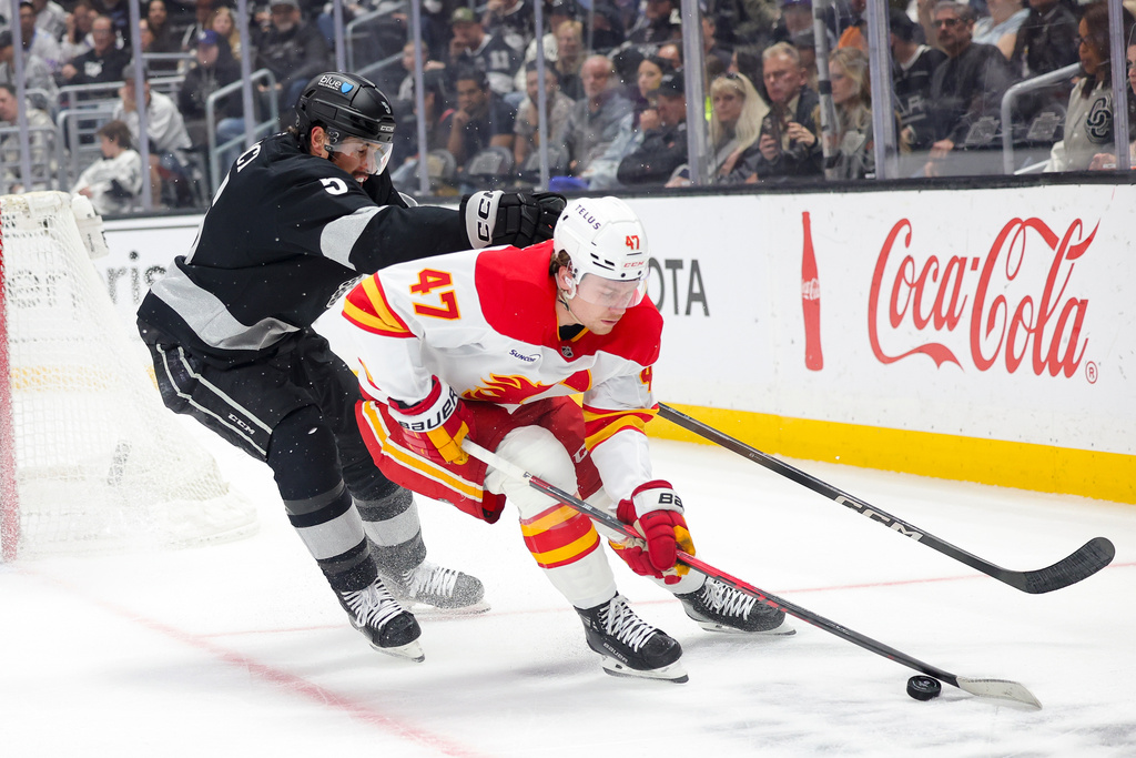 Calgary Flames center Connor Zary, right, moves the puck against Los Angeles Kings defenseman Cody Ceci during the first period of an NHL hockey game Saturday, Feb. 28, 2026 in Los Angeles. (AP Photo/Ryan Sun)