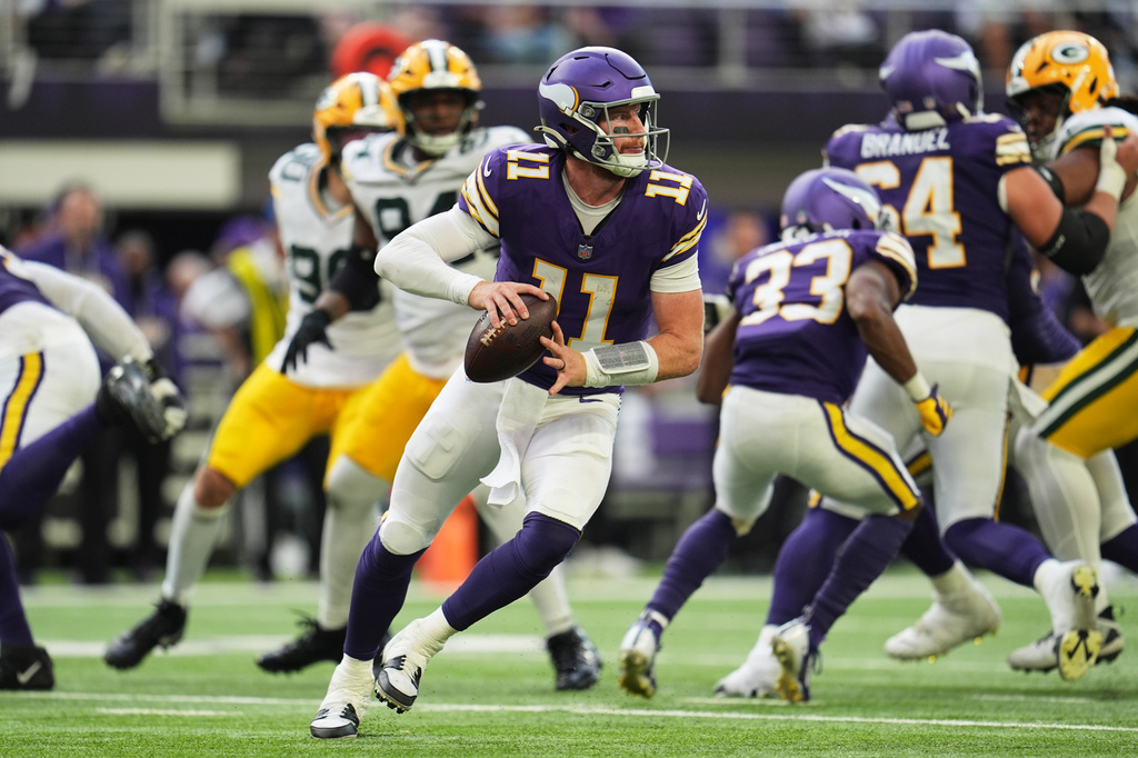 Minnesota Vikings quarterback Carson Wentz (11) rolls out of the pocket before throwing a pass during the second half of an NFL football game against the Green Bay Packers, Sunday, Sept. 13, 2026, in Minneapolis, Minn. (AP Photo/Abbie Parr)
