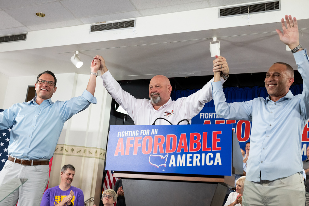 Pennsylvania Gov. Josh Shapiro, left, Democratic congressional candidate Bob Brooks, center, and U.S. House Democratic Leader Hakeem Jeffries raise their hands during a campaign event for Brooks ahead of the midterm elections at a Steelworkers Union Hall in Bethlehem, Pa., Sunday, July 26, 2026. (AP Photo/Erin Blewett)