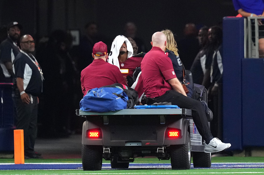 Washington Commanders quarterback Jayden Daniels (5) is carted off the field after an apparent injury in the first half against the Dallas Cowboys during an NFL football game in Arlington, Texas, Sunday, Sept. 20, 2026. (AP Photo/Julio Cortez)
