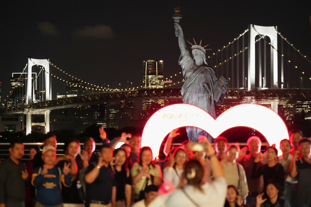 Visitors pose for a photo near the replica of the Statue of Liberty at Odaiba Seaside Park in Tokyo, Wednesday, June 17, 2026. (AP Photo/Hiro Komae)