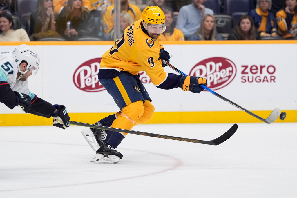 Nashville Predators left wing Filip Forsberg (9) hits the puck past Seattle Kraken center Shane Wright (51) during the third period of an NHL hockey game Thursday, March 19, 2026, in Nashville, Tenn. (AP Photo/George Walker IV)