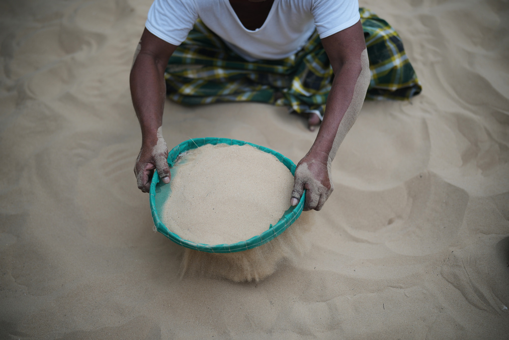 Adnan, only one name given, uses a sieve to clean sand in a sandpit in a neighbour's home in Legung Timur village in Sumenep on Madura Island, Indonesia, Tuesday, Sept. 9, 2025. (AP Photo/Dita Alangkara)
