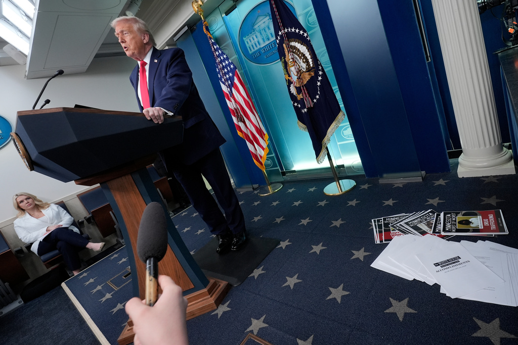 President Donald Trump speaks as White House press secretary Karoline Leavitt listens in the James Brady Press Briefing Room at the White House, Tuesday, Jan. 20, 2026, in Washington. (AP Photo/Alex Brandon)