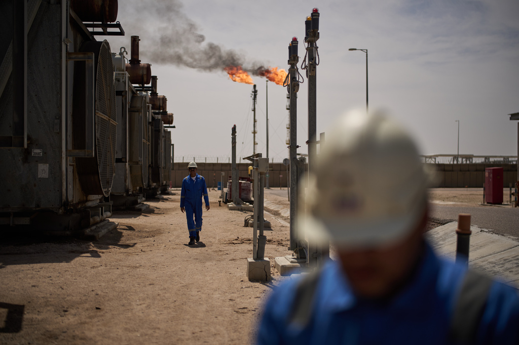 FILE - Workers walk in the Zubair oil field, whose operations have being reduced since the start of the Iran war, near Basra, Iraq, March 28, 2026. (AP Photo/Leo Correa, File)