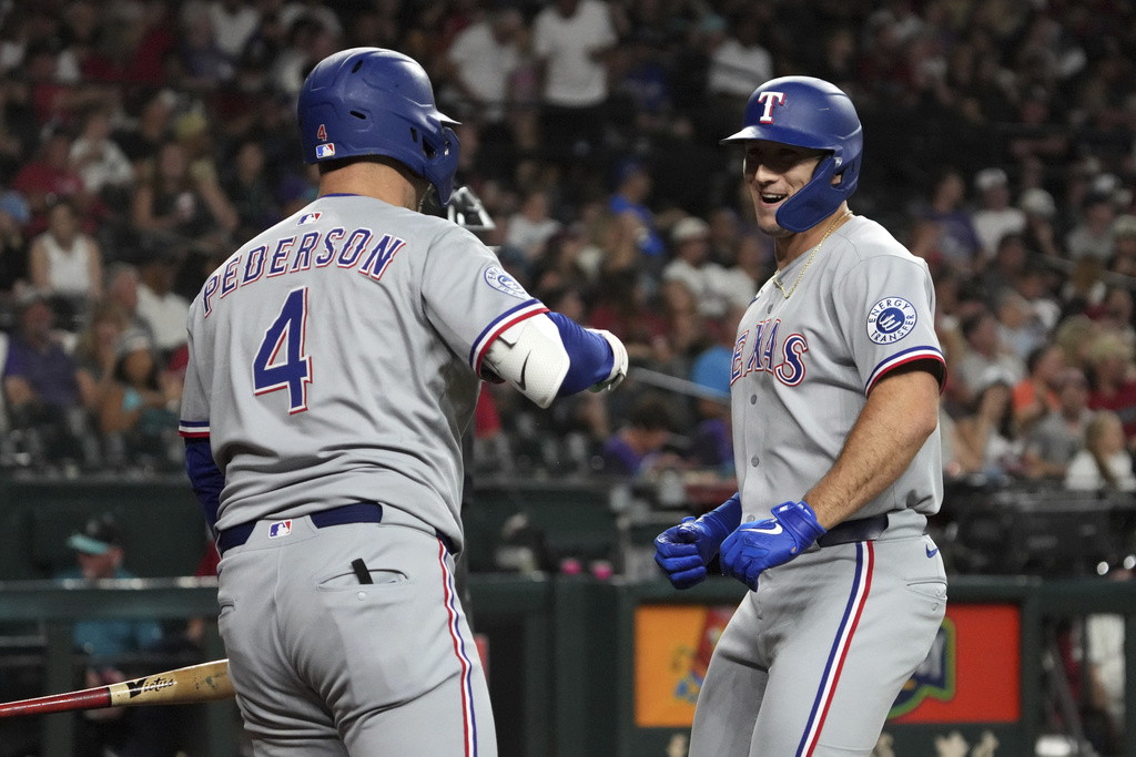 Texas Rangers' Wyatt Langford, right, celebrates with Joc Pederson (4) after hitting a solo home run against the Arizona Diamondbacks in the sixth inning of a baseball game, Monday, Sept. 1, 2025, in Phoenix. (AP Photo/Rick Scuteri)
