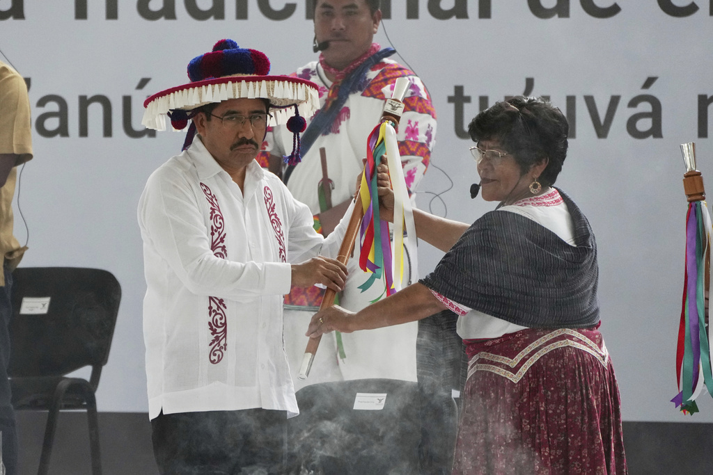Mexico's incoming Supreme Court president Hugo Aguilar, left, receives a baton from a representative of Indigenous and Afro-Mexican people before being sworn in, at the Zocalo, Mexico City's main square, Monday, Sept. 1, 2025. (AP Photo/Fernando Llano)