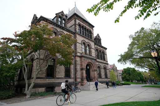 FILE - Passers-by walk and ride along a path on the campus of Brown University, in Providence, R.I., Monday, Oct. 12, 2020. (AP Photo/Steven Senne, File) FILE - Passers-by walk and ride along a path on the campus of Brown University, in Providence, R.I., Monday, Oct. 12, 2020. (AP Photo/Steven Senne, File)