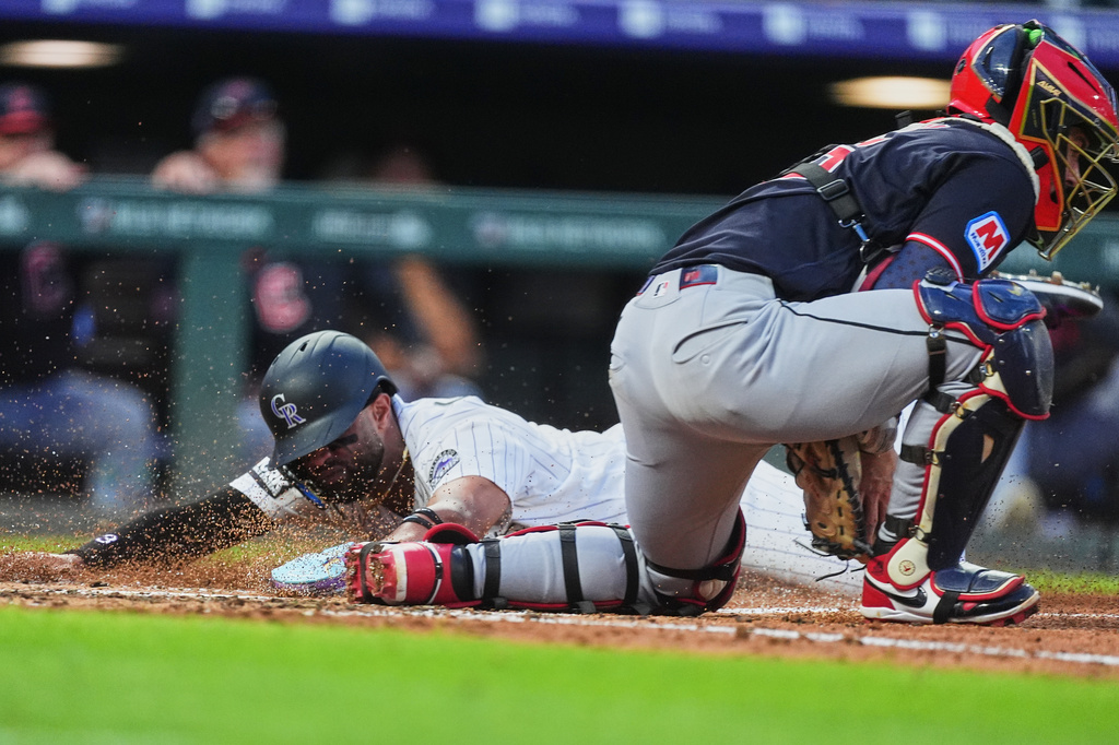 Colorado Rockies' Willi Castro, left, scores on a double hit by Troy Johnston as Cleveland Guardians catcher Patrick Bailey, right, fields the throw in the fourth inning of a baseball game Saturday, Aug. 22, 2026, in Denver. (AP Photo/David Zalubowski)