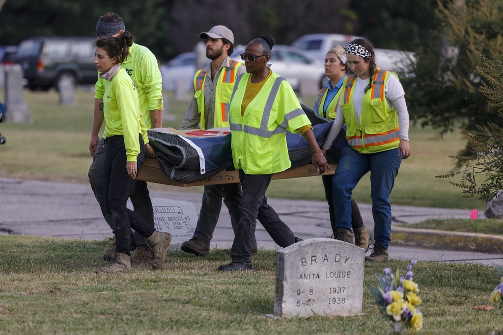 FILE - Researchers and burial oversight committee member Brenda Alford carry the first set of remains exhumed from the latest dig site in Oaklawn Cemetery to an onsite lab for further examination, Sept. 13, 2023, in Tulsa, Okla. A third set of remains with a gunshot wound has been found in the search for graves of victims of the 1921 Tulsa Race Massacre at a Tulsa cemetery, according to a state official. (Mike Simons/Tulsa World via AP, File)