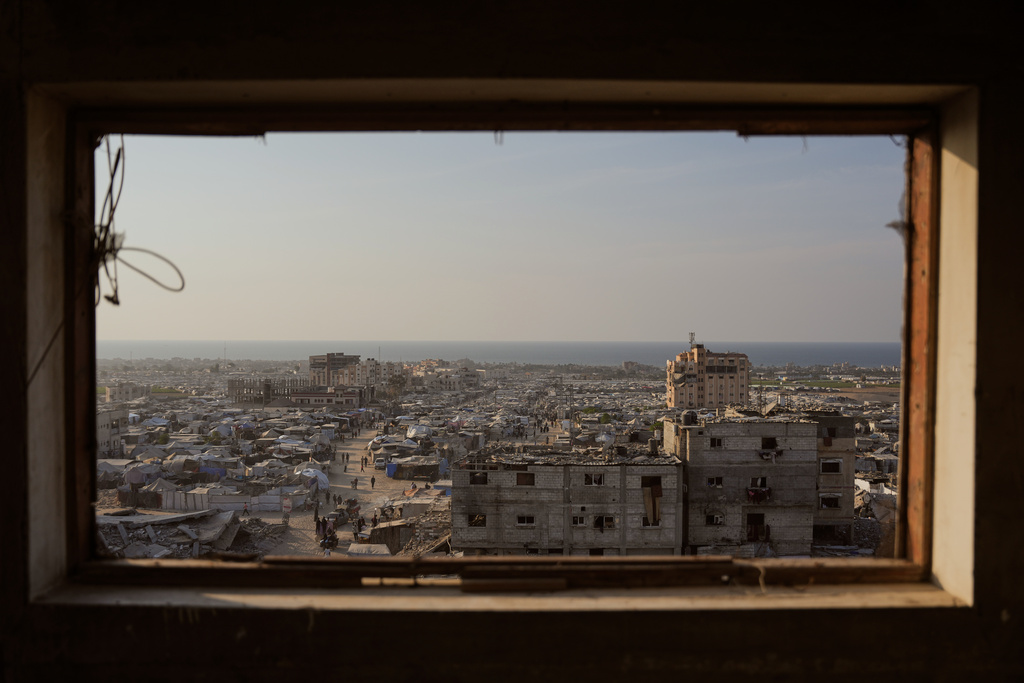 Displaced Palestinians walk through a makeshift tent camp in the Muwasi area of Khan Younis, in the Gaza Strip, Saturday, Nov. 8,2025. (AP Photo/Abdel Kareem Hana)