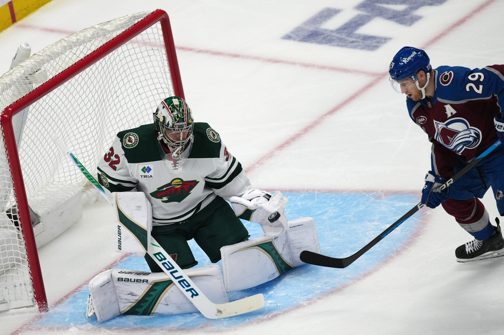 Colorado Avalanche center Nathan MacKinnon, right, redirects the puck at Minnesota Wild goaltender Filip Gustavsson in the third period of Game 2 of an NHL hockey Stanley Cup second-round playoff series Tuesday, May 5, 2026, in Denver. (AP Photo/David Zalubowski)