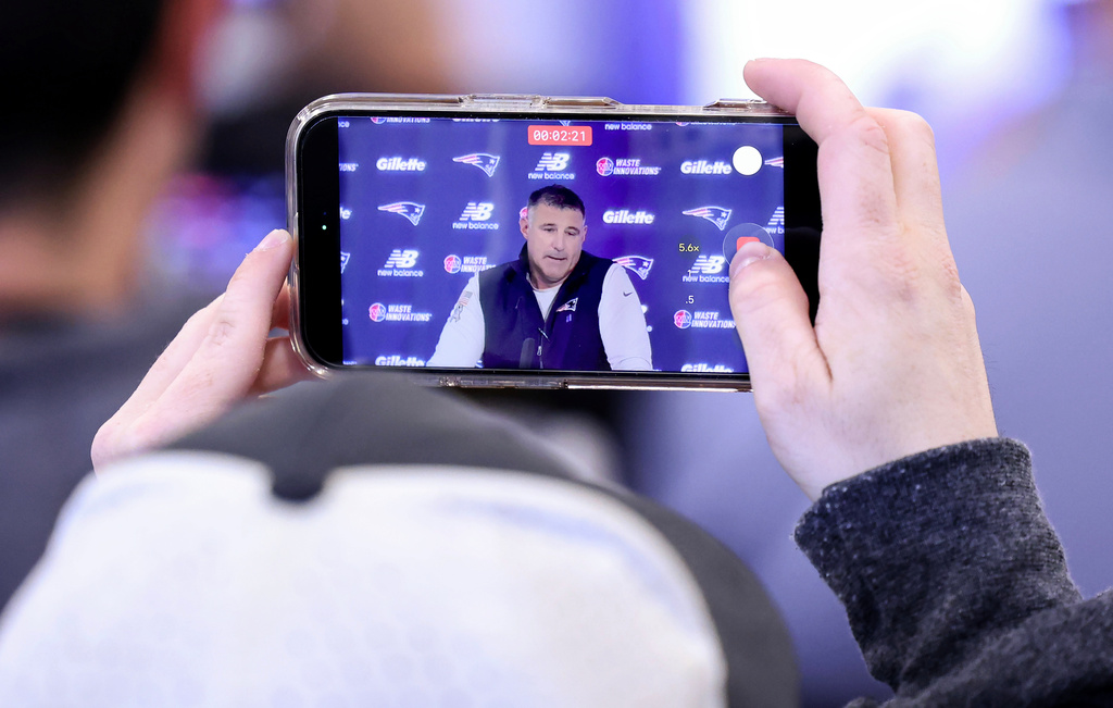 New England Patriots head coach Mike Vrabel, displayed on a mobile phone, speaks during an NFL football press conference, Tuesday, April 21, 2026, in Foxborough, Mass. (AP Photo/Mark Stockwell)