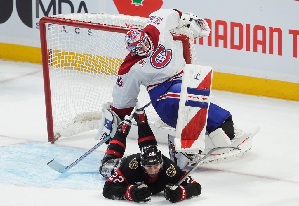 Montreal Canadiens goaltender Samuel Montembeault (35) grabs the net as Ottawa Senators right wing Michael Amadio (22) slides into him during the second period of an NHL hockey game, in Ottawa, Ontario, Saturday, Jan. 17, 2026. (Adrian Wyld/The Canadian Press via AP)