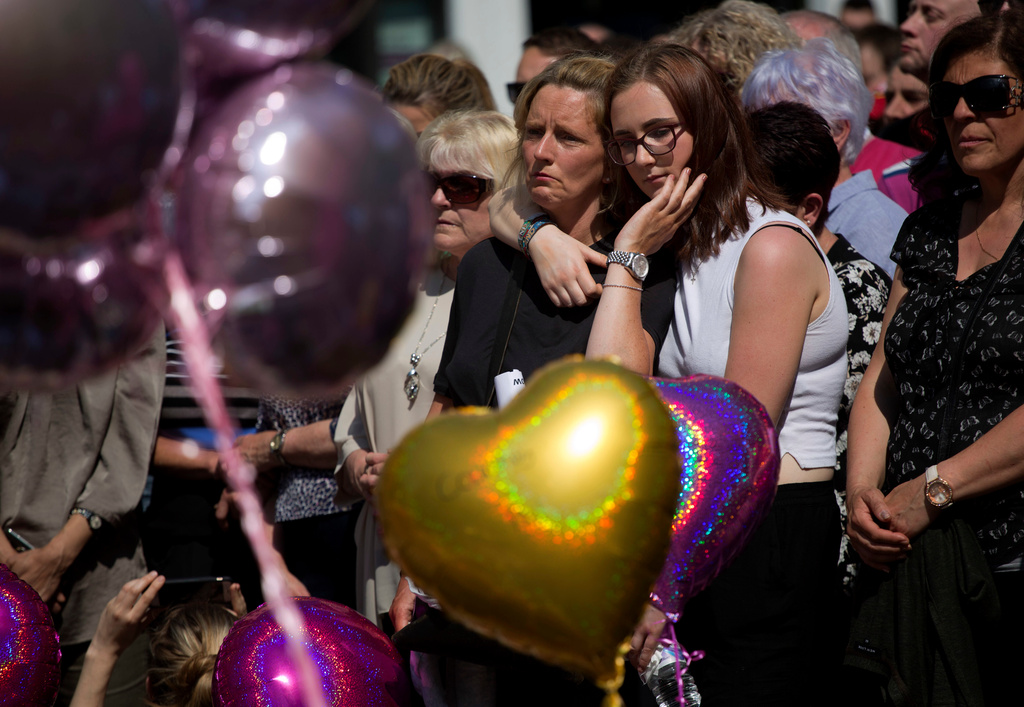 FILE - People hold a minute of silence in a square in central Manchester, England, on May 25, 2017, after a suicide bombing attack at an Ariana Grande concert at the Manchester Arena. (AP Photo/Emilio Morenatti, File)