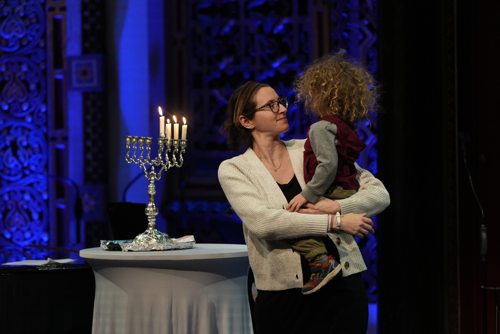 Rebecca Weintraub, assistant rabbi of New York City's B'nai Jeshurun congregation, holds her son during a Hannukah party at the synagogue on Tuesday, Dec. 16, 2025. (AP Photo/Luis Andres Henao)