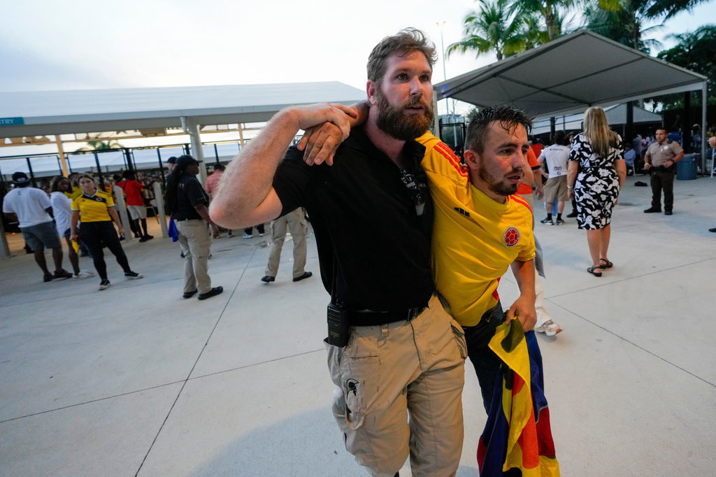 FILE - A security agent assists a fan who was waiting to enter the stadium prior to the Copa America final soccer match between Argentina and Colombia, in Miami Gardens, Fla., July 14, 2024. (AP Photo/Lynne Sladky, File)