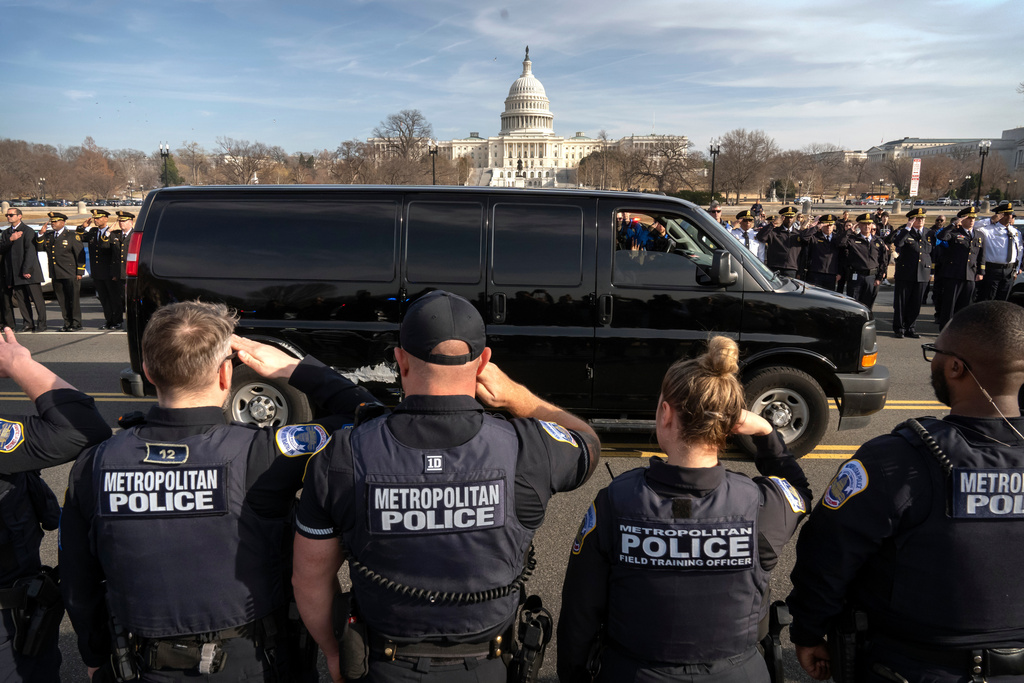 Metropolitan Police Department officers salute as a van carrying the body of MPD officer Terry Bennett, who died on Wednesday, weeks after being struck by a motorist, is driven past the Capitol, Thursday, Jan. 8, 2026, in Washington. (AP Photo/Mark Schiefelbein)