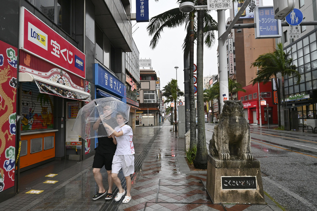 People walk in the rain as typhoon Dolphin approaches the city, in Naha, Japan, Friday, Aug. 7, 2026. (Satsuki Watarai/Kyodo News via AP)