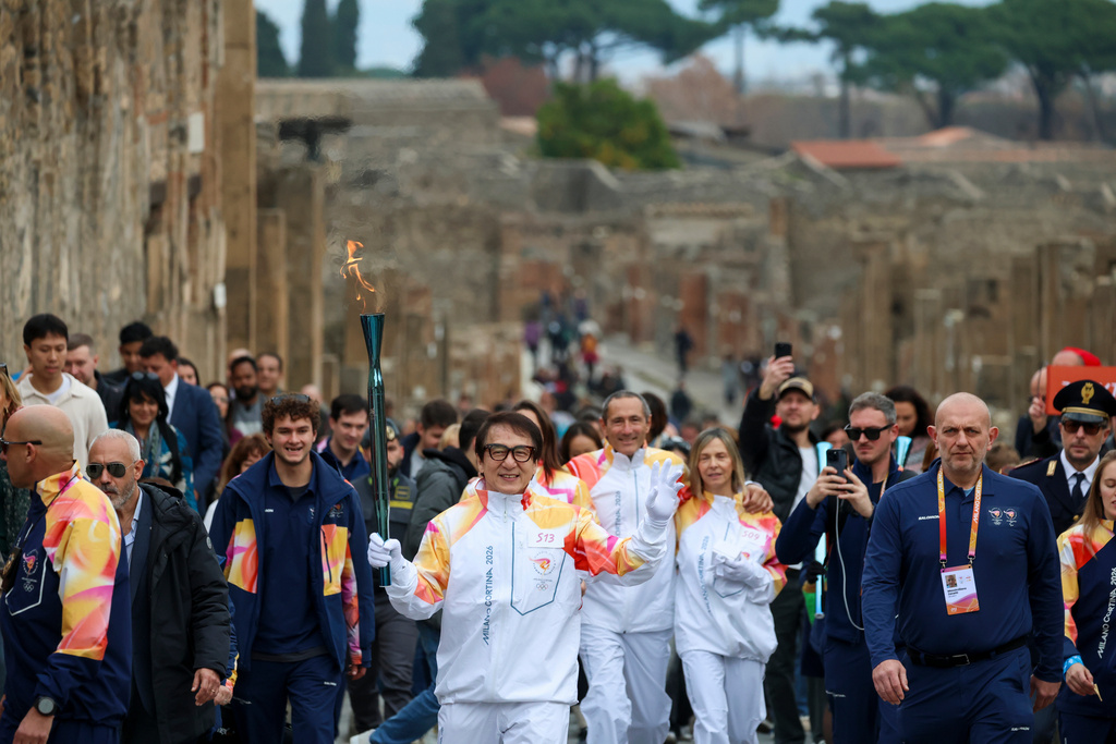 Actor Jackie Chan holds the olympic torch passing through the Archaeological Park in Pompeii, Italy, Monday, Dec. 22, 2025. (Alessandro Garofalo/LaPresse via AP)
