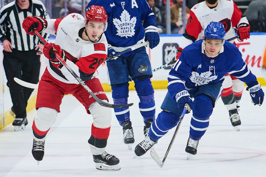 Carolina Hurricanes' Sebastian Aho (20) and Toronto Maple Leafs' Max Domi (11) battle for the puck during first-period NHL hockey game action in Toronto, Friday, March 20, 2026. (Sammy Kogan/The Canadian Press via AP)